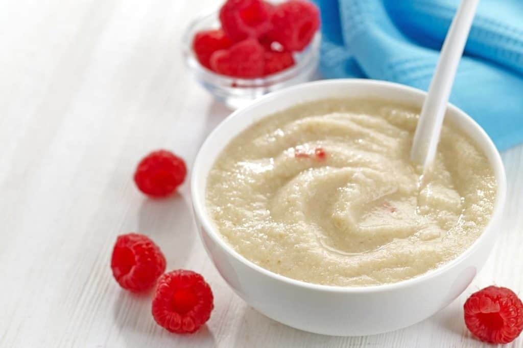 Bowl of baby cereal with raspberries.