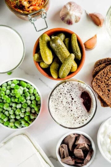 a collage of gut healthy foods like yogurt, kombucha, peas, pickles, fread, kimchi, sauerkraut.
