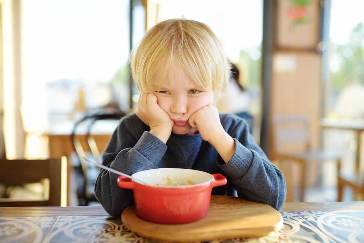 Toddler sitting at table grumpy.