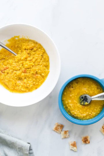 A side by side image of moong dal with the left bowl being suitable for the whole family and the right bowl being just right for baby. Paratha on side for dipping.